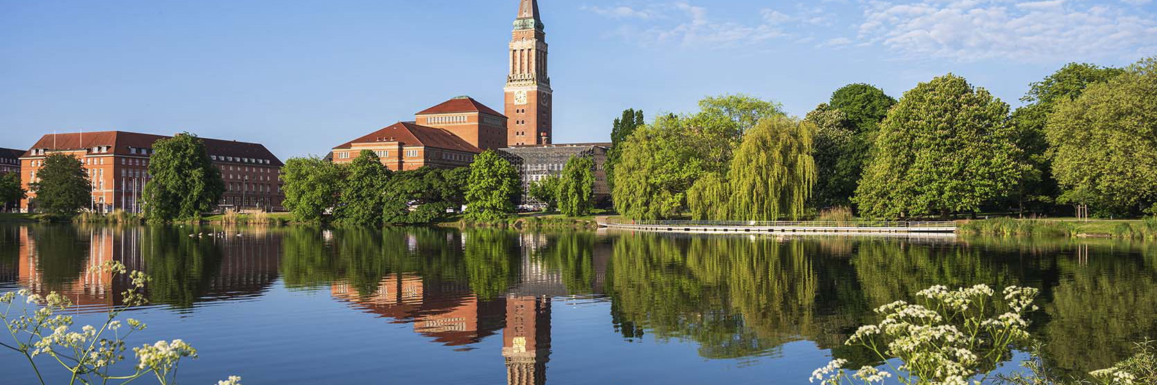 A lakeside civic building and clock tower reflected in the water, Kiel