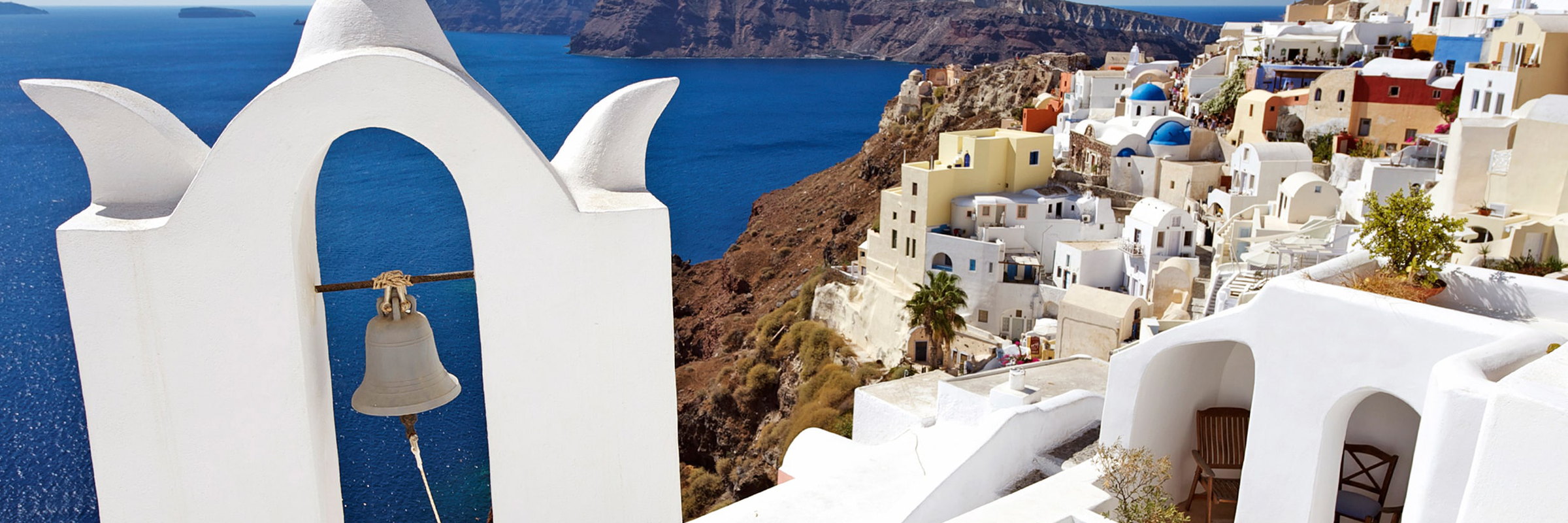 A whitewashed bell tower above the caldera, with the village climbing the cliff